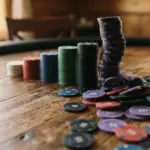 A close-up, low-angle shot of a progression of colorful poker chip stacks on a warm, tactile wooden surface